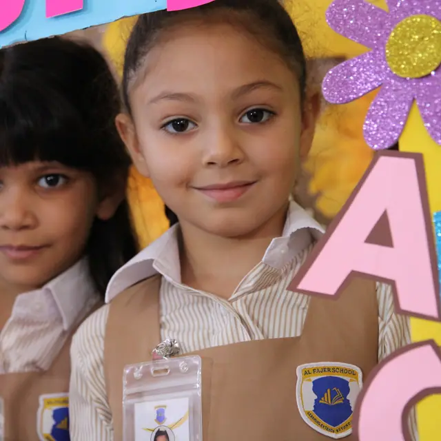 Two smiling pupils holding welcome crafts, the AFS crest on their uniforms