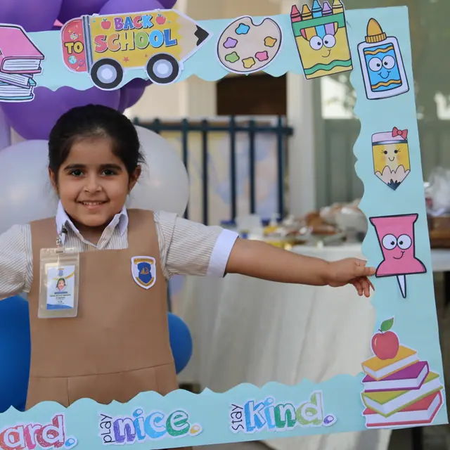A beaming girl posing inside the decorated Back to School frame