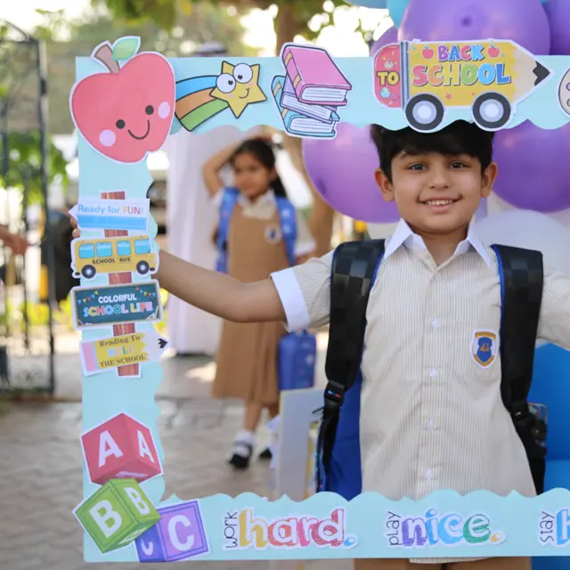 A boy with a backpack grinning through the Back to School frame