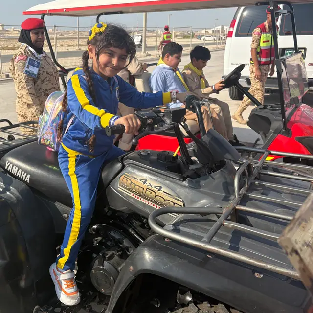 A girl with braids and yellow hair flowers smiling on an ATV