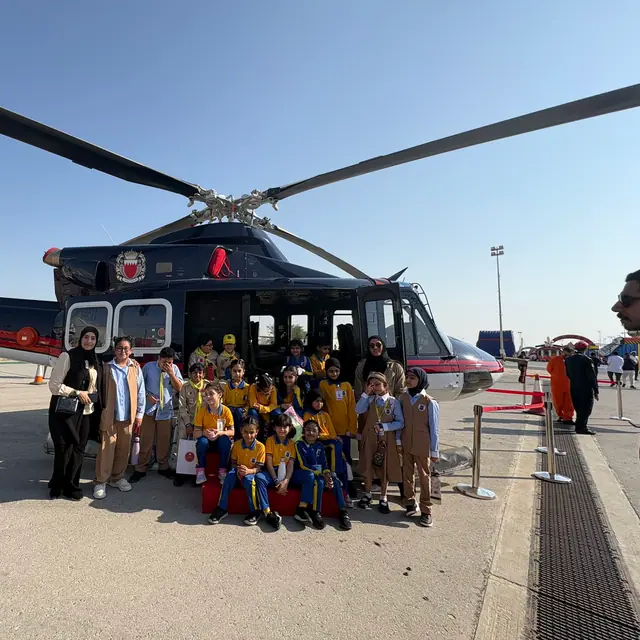 A class posing with teachers in front of a police helicopter on a field trip