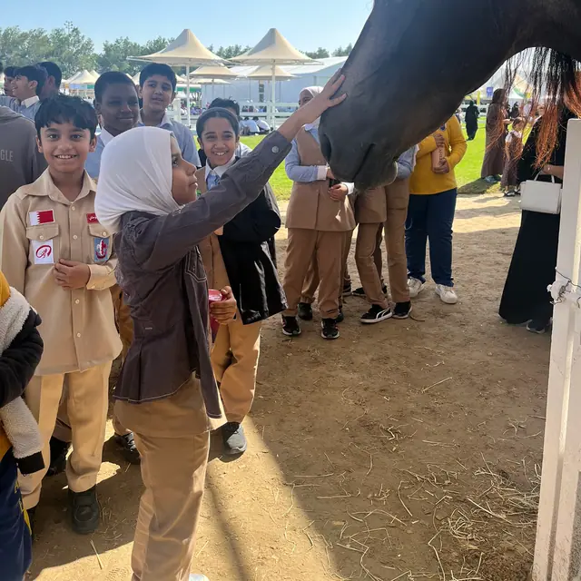 Smiling pupils gathered around as a classmate strokes a horse