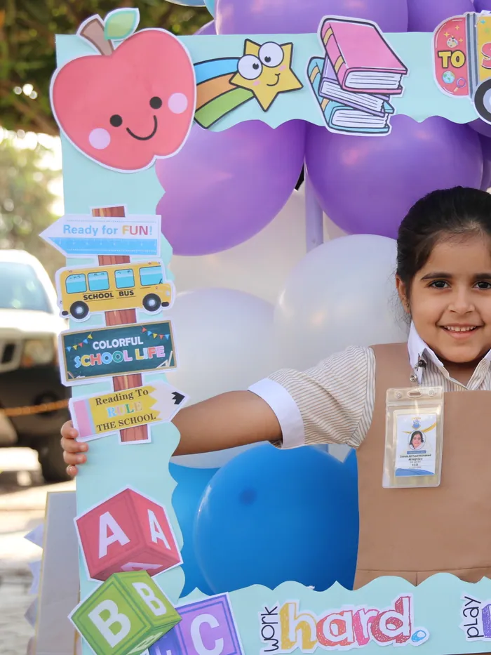 A beaming pupil posing in the Back to School photo frame on her first day