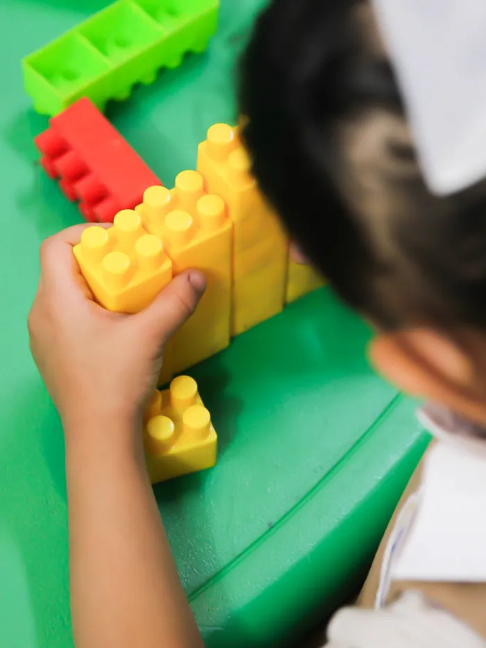A child's hands building with colourful blocks