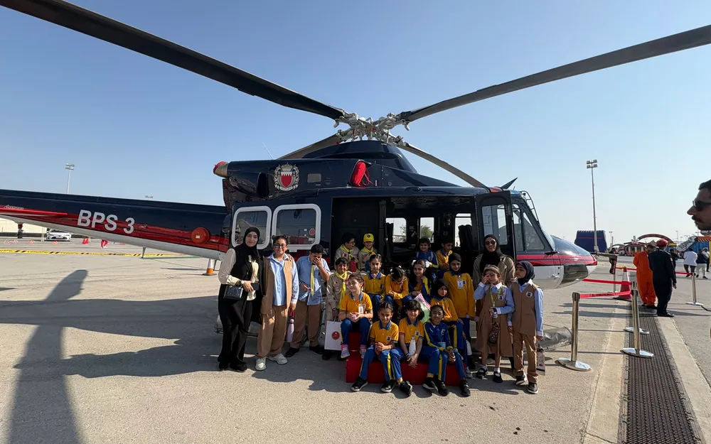 An AFS class posing with teachers in front of a Bahrain police helicopter