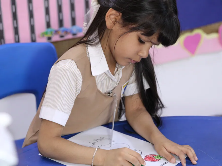 A focused pupil colouring at a blue classroom table