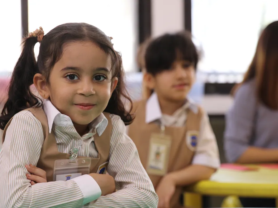 A confident pupil smiling with arms crossed at her desk